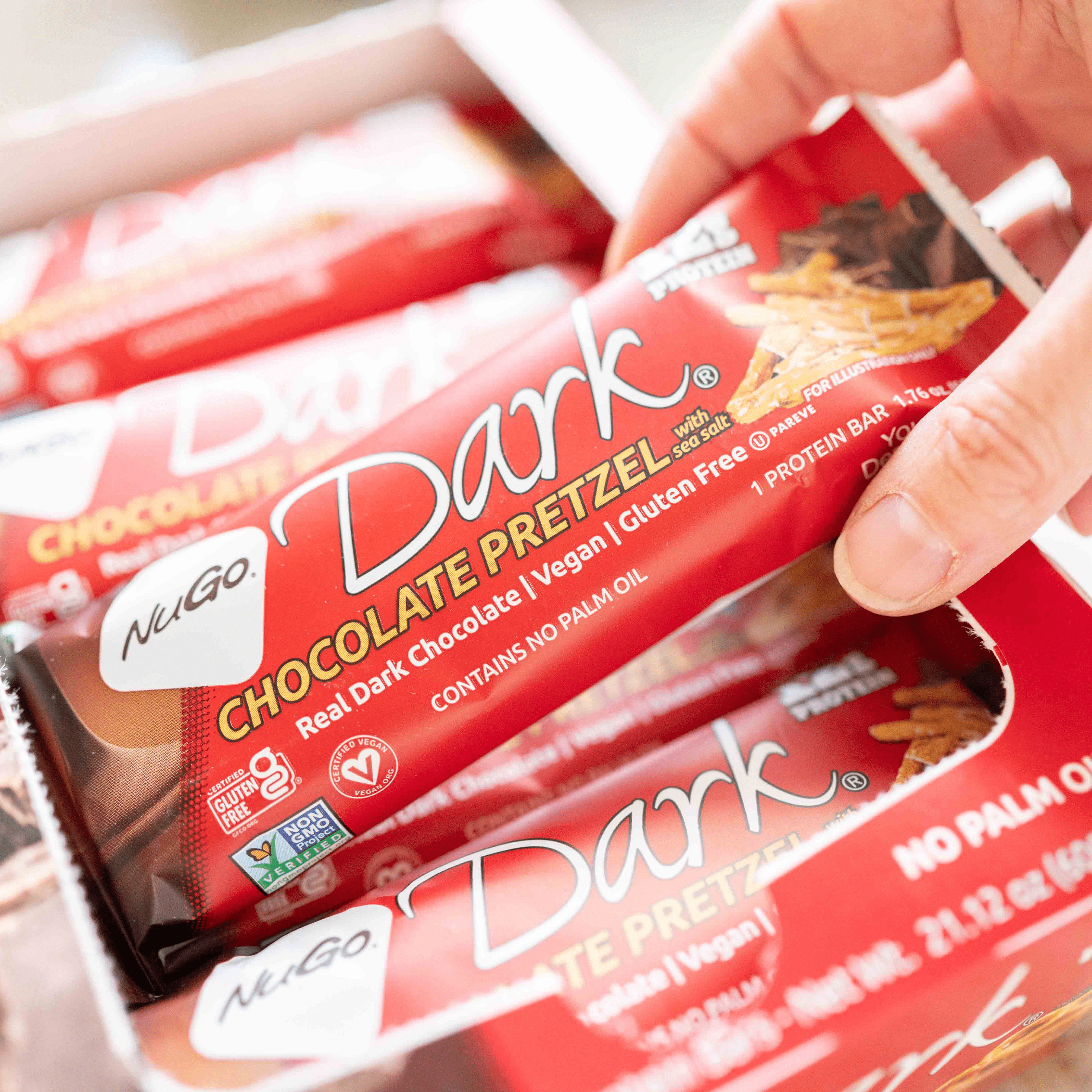 NuGo Dark Chocolate Pretzel bar being grabbed from tray